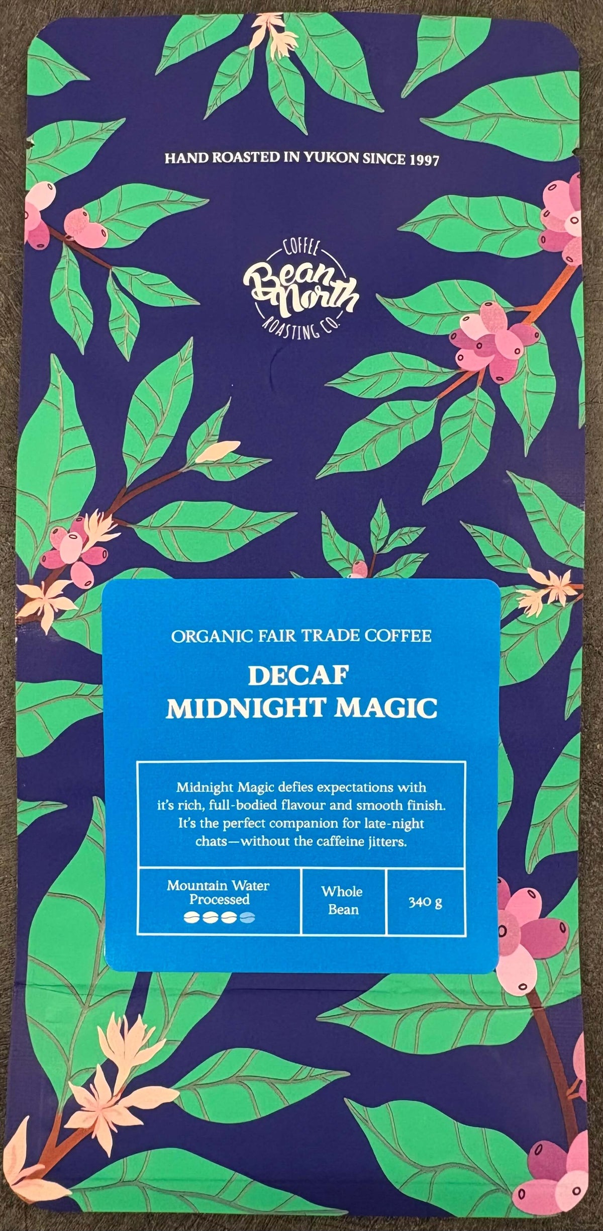 Decaf Midnight Magic coffee package with floral design on a dark background
